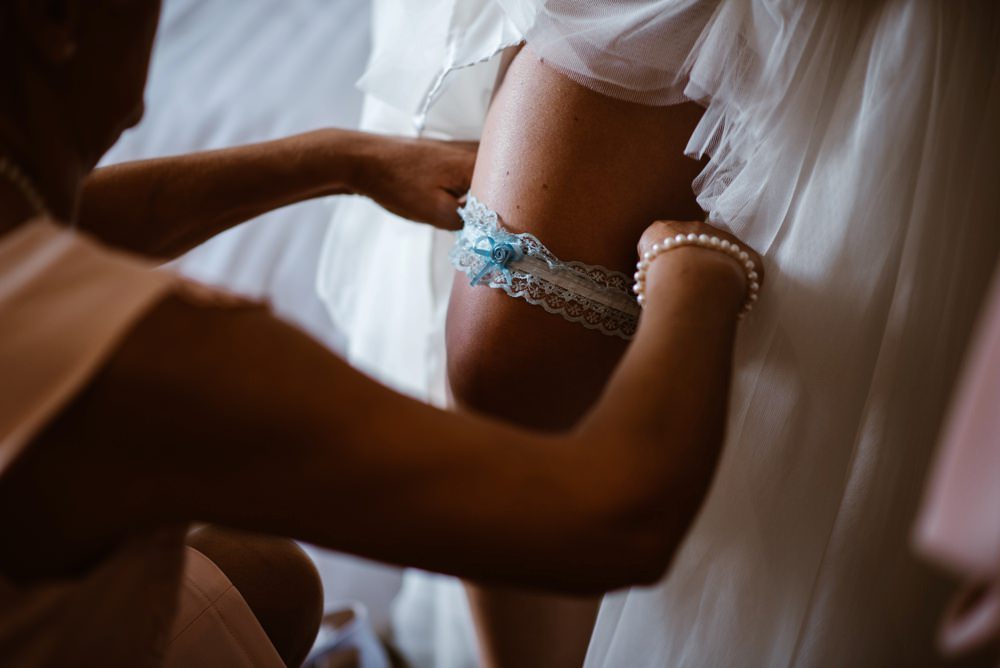 bridesmaid putting garter in bride