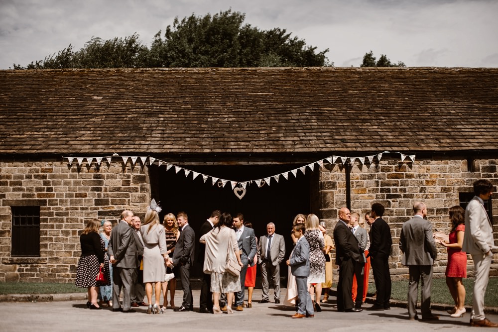 Rustic barn setting, guests outside the venue with bunting hung.