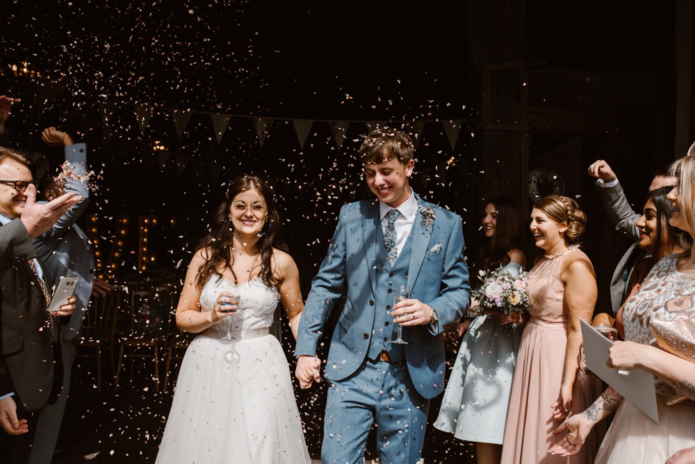 Couple exit rustic barn to a flurry of confetti 
