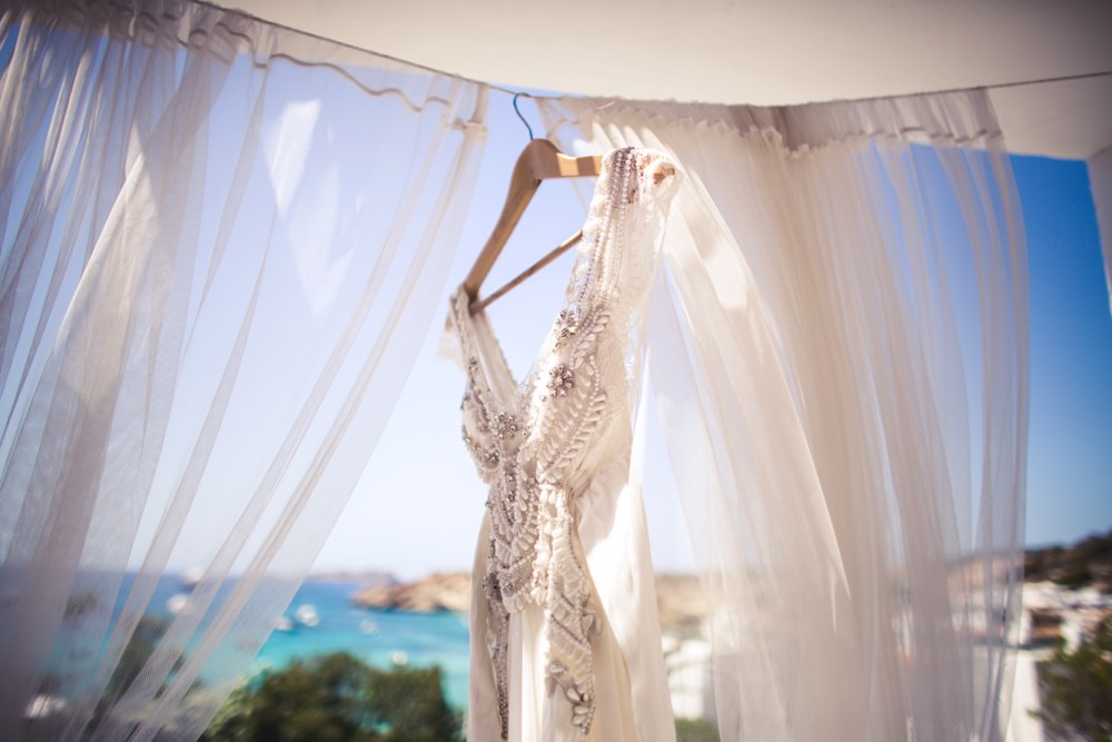 Bride's beautiful Anna Campbell dress hung up with the sea in the background.