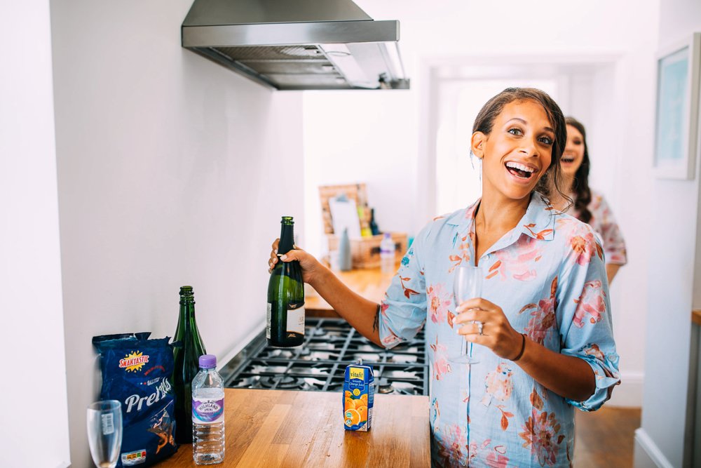 bridesmaid laughing in kitchen getting champagne