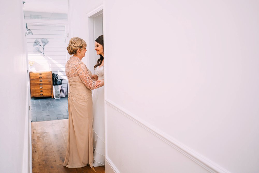 Bride and mother share a moment in the doorway