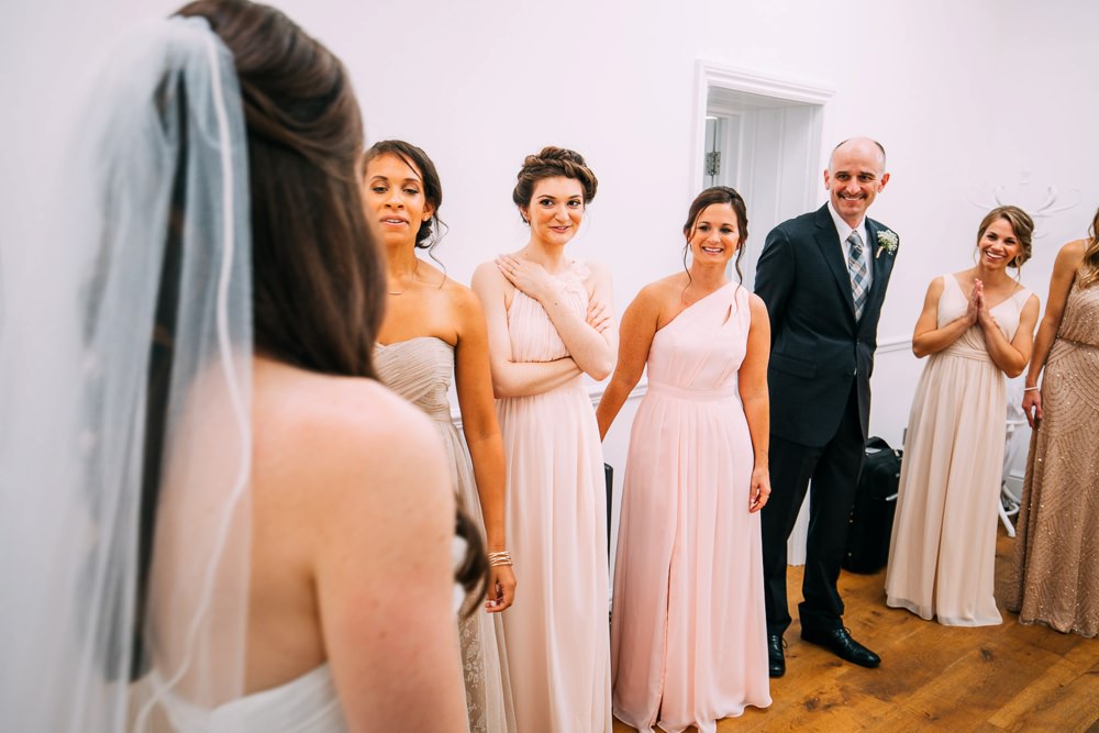The bride is ready and the bridesmaids and her dad gather around her